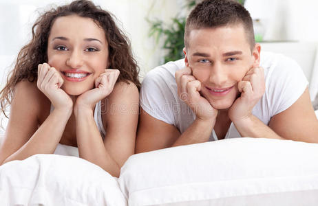 微笑着躺在床上相爱的年轻夫妇