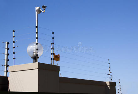 头顶上的灯围墙顶上的电子围栏和安全摄像头照片