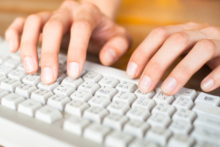 女的手在电脑键盘上键入文本的照片