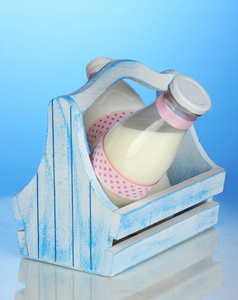 在蓝色背景上的木制框中瓶牛奶