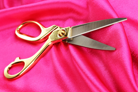 在粉红色的织物上的金属剪刀