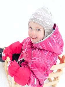 可爱的小女孩坐在雪橇的肖像图片