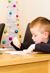年轻的男孩在一个表上用铅笔绘图