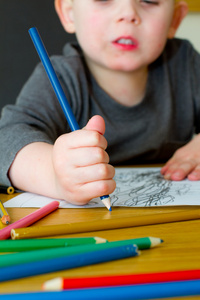 年轻的男孩在一个表上用铅笔绘图