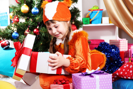 小女孩穿着西装的松鼠在欢乐地装饰的屋子中打开礼物