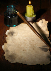旧纸与附近照明蜡烛木桌上的墨水笔