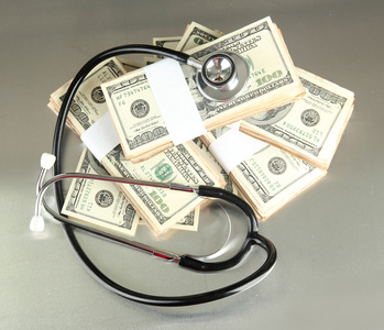 医疗成本的概念 听诊器和美元在灰色的背景上