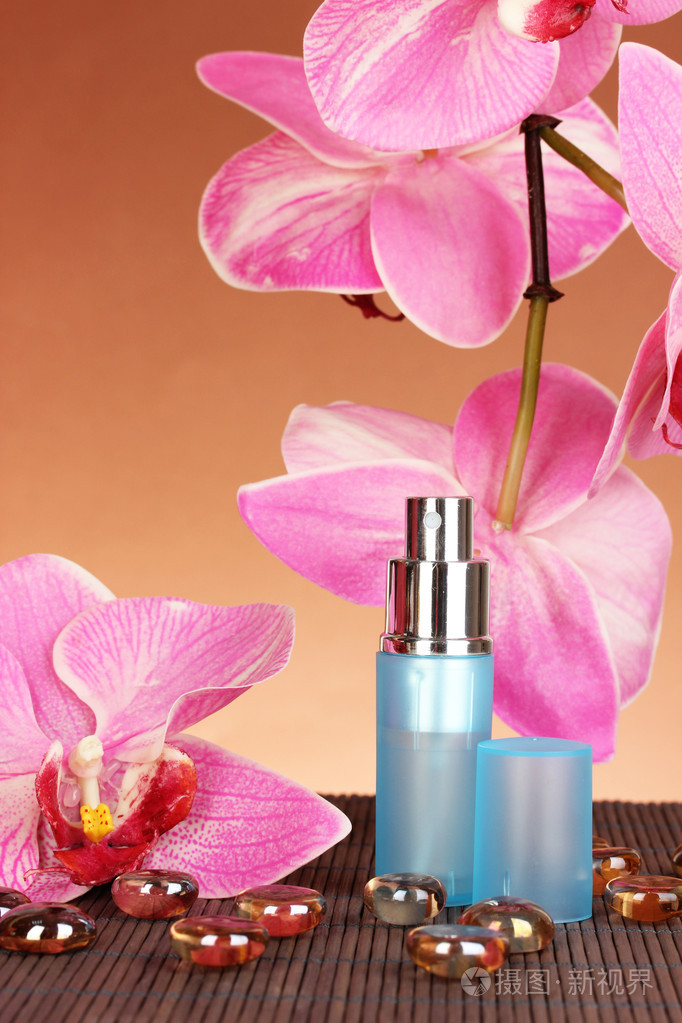 漂亮的瓶子里棕色背景上的兰花的女性香水