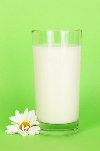 一杯新鲜新牛奶绿色背景上的白花