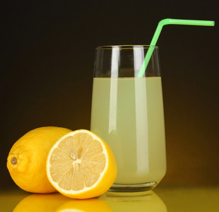 在玻璃和它旁边暗橙色背景上的柠檬美味柠檬汁