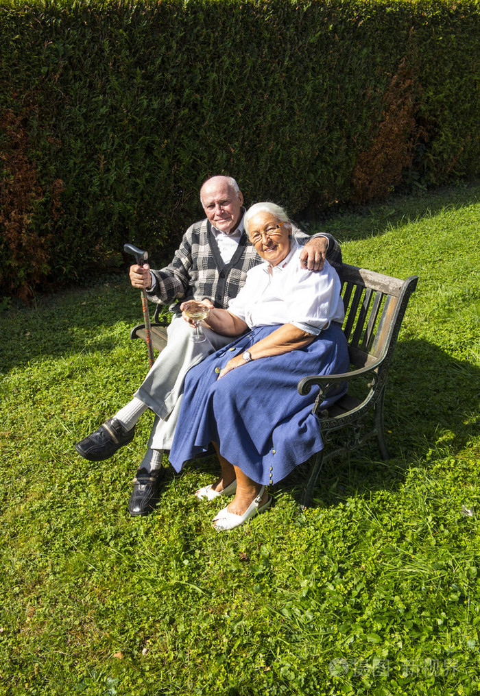 老人夫妇坐在他们的花园和享受生活