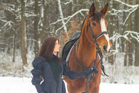 美丽的女人和马在冬季