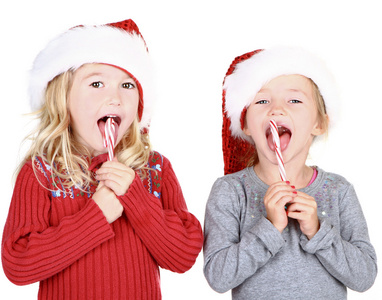 两个孩子穿上圣诞老人的帽子吃糖果