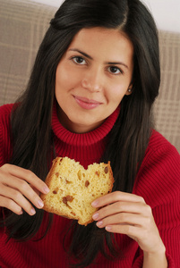 西班牙裔美国人的年轻女子吃圣诞面包，吃面包的年轻女子