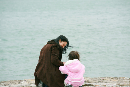后视图的母亲和女儿在美丽的春天海