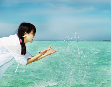 时尚美丽亚洲女孩玩水在马尔代夫海滩附近