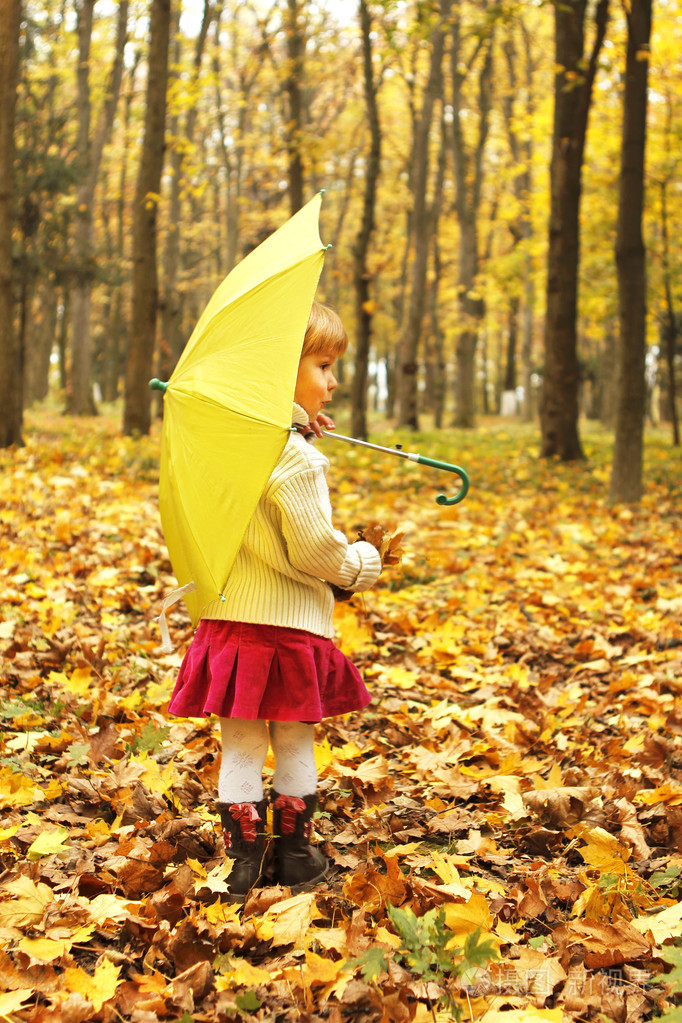 漂亮的小女孩在秋天的森林与伞