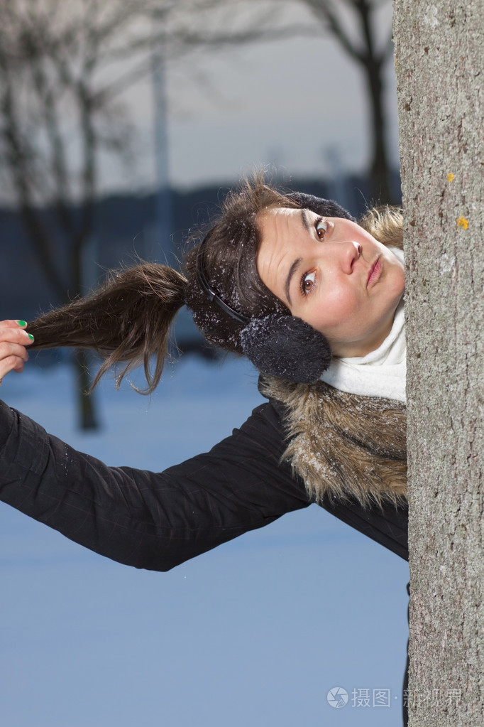 美丽的女孩躲在树之外