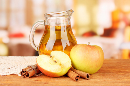 苹果汁和苹果在明亮的背景上的木桌上的充分 jug