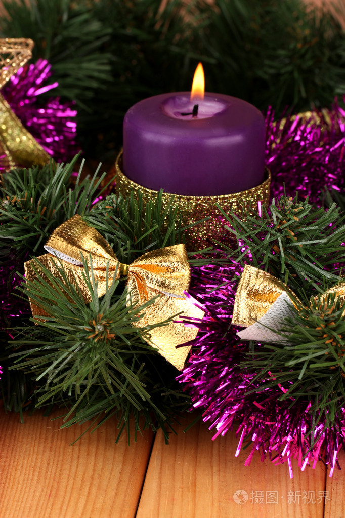 圣诞蜡烛和装饰品的木制背景上的紫色和金色颜色组成