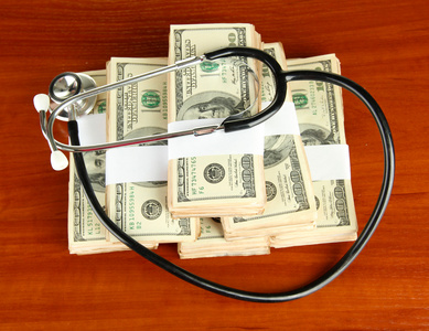 医疗成本的概念 听诊器和木制背景美元