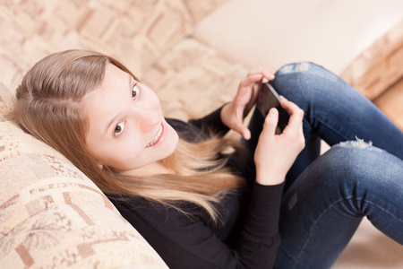 快乐少女坐在客厅沙发上的手机