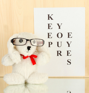 视力测试图与眼镜和玩具上木制背景特写