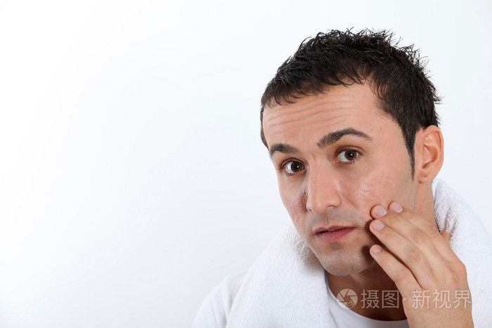 年轻人把保湿产品放在他脸上的特写