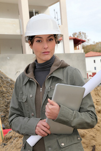 与白色安全头盔站在建筑工地上的女工程师