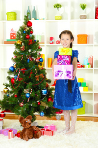 持有礼品盒圣诞节树附近的小女孩