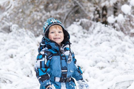 蹒跚学步男孩在冬季一天玩雪