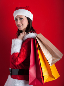 持有购物袋红色背景上孤立的圣诞老人帽子圣诞女人
