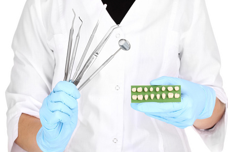牙医手与牙科工具和义齿的蓝色医疗手套