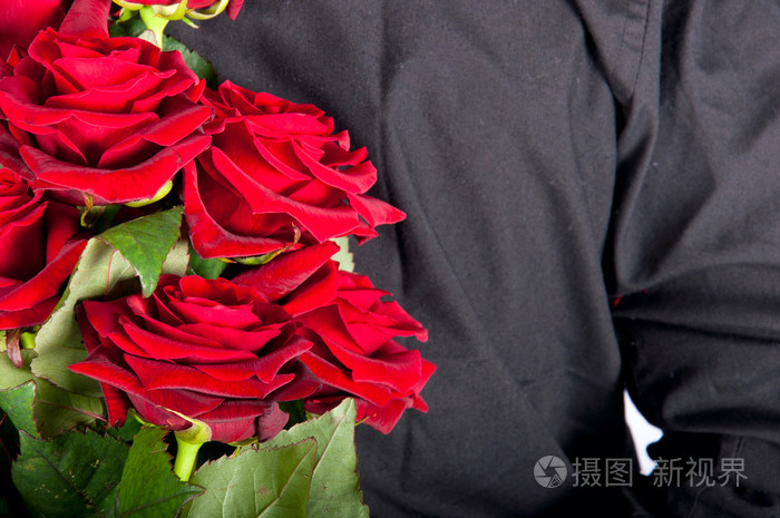 一个男人举在他背后的红玫瑰的图片