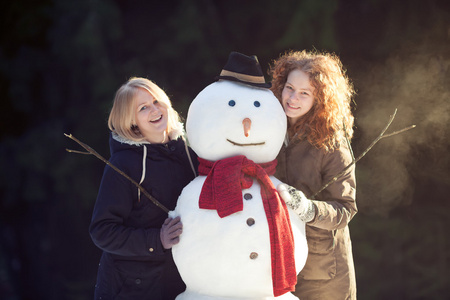 两个年轻妇女拥抱雪人