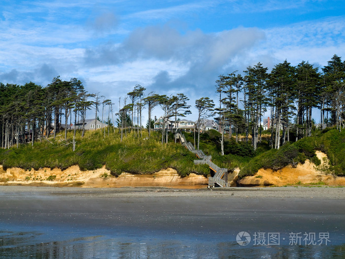 木制楼梯下树木繁茂的山坡上通往海滩