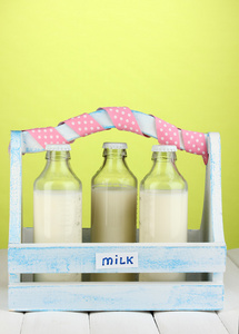 在绿色背景上的木桌上的木盒装瓶牛奶