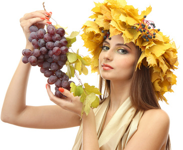 美丽的年轻女子，与黄色秋季花圈和葡萄，孤立在白色