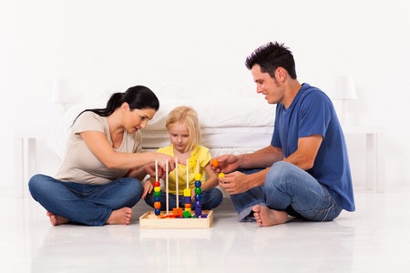 年轻的家庭在卧室地板上玩教育玩具
