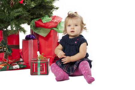 可爱的姑娘坐在由圣诞树和圣诞的肖像