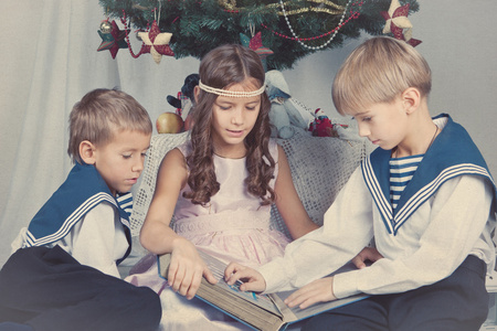 三个孩子都围坐在圣诞树