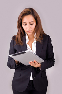灰色背景上平板电脑的年轻商业女人