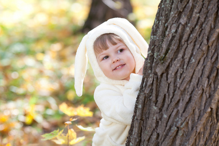 漂亮的小女孩在服装小兔子在秋天的森林中