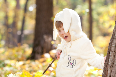 漂亮的小女孩在服装小兔子在秋天的森林中