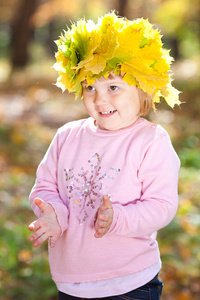 漂亮的小女孩在一个花圈枫叶叶子在秋季前