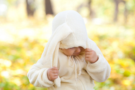 漂亮的小女孩在服装小兔子在秋天的森林中