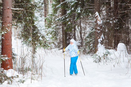 年轻的女子在回来的时候在冬季森林滑雪滑雪看