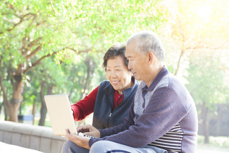 快乐的高级夫妇与便携式计算机在互联网上冲浪