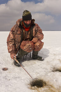 一名男子在冰上钓鱼钓到鱼