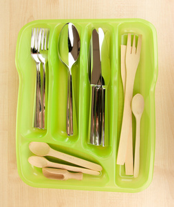 与检查的餐具和木勺子木桌上的绿色塑料餐具托盘